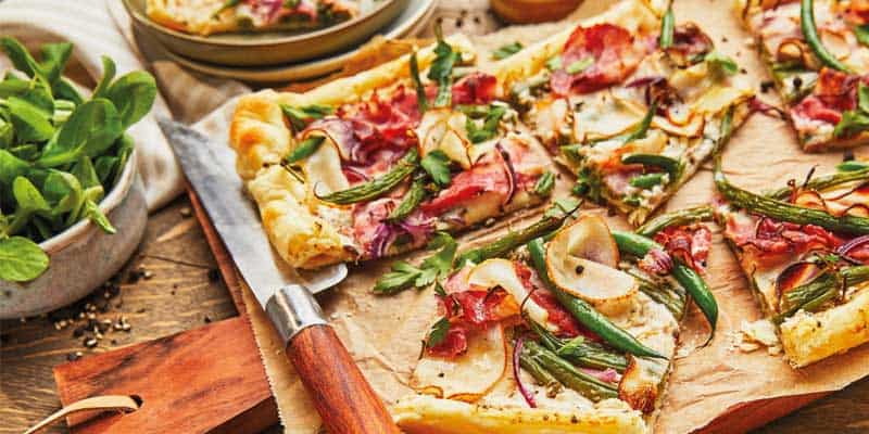Tarte, belegt mit Birnen, Bohnen und Speck